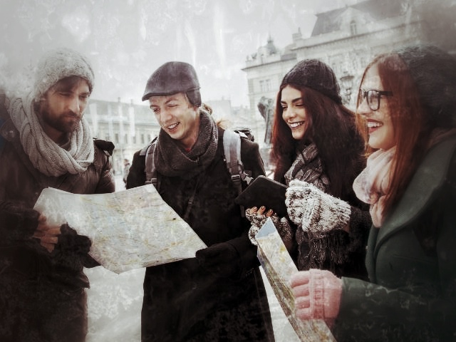 Gruppe von vier Personen mit Karte beim Erkunden einer Stadt im Winter