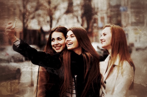 Drei junge Frauen mit rötlichem Haar machen gemeinsam Selfie in der Stadt