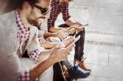 Gruppe von Personen schaut auf Smartphones, Stadtrallye-Teilnehmer mit Geräten