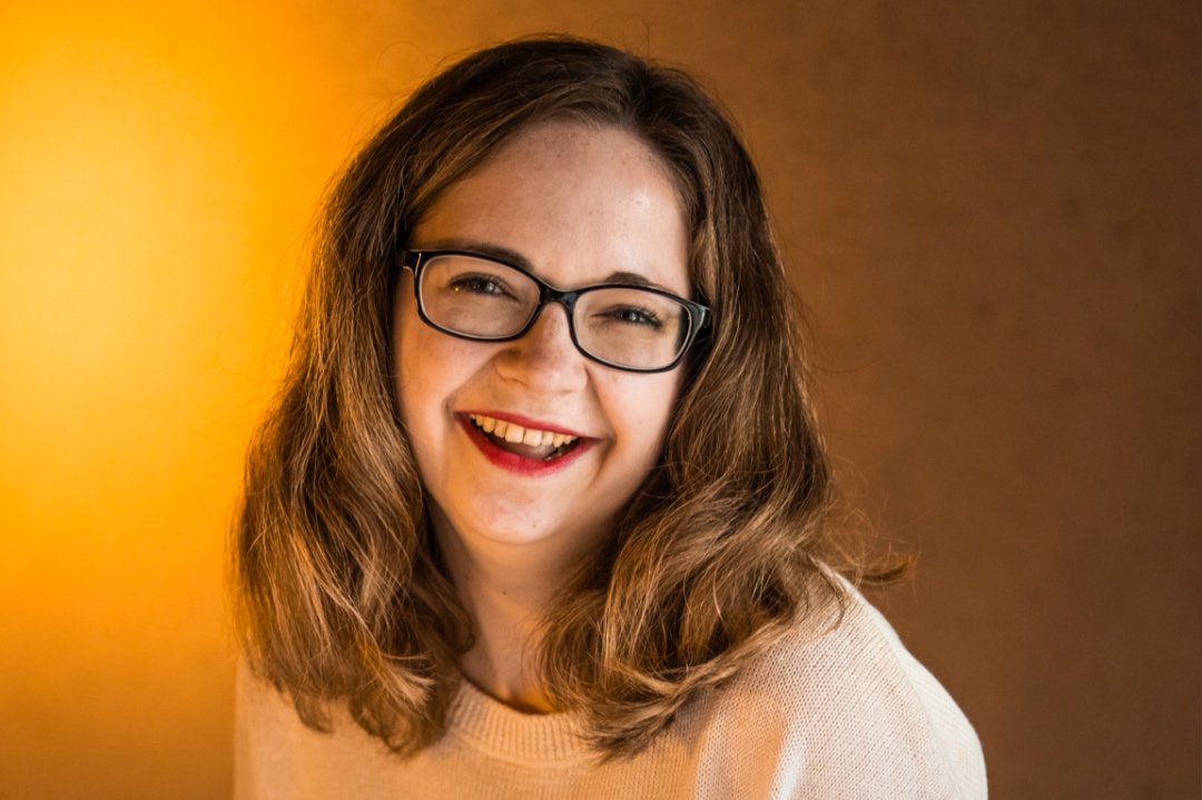 Selflove Vibes – Onlinekurs für mehr Selbstwert von Marie Kremer 7 Porträt Marie Kremer lächelnd mit rotem Lippenstift und Brille vor orange-gelbem Hintergrund