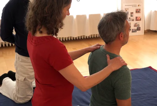 Unterrichtsszene Shiatsu in Sitzposition Therapeutin behandelt Schüler