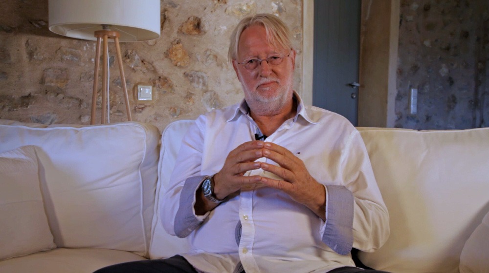 Dieter Broers sitzt auf Sofa weißes Hemd spricht