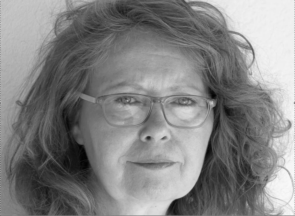 Schwarz-Weiß-Porträt einer Frau mit lockigem Haar, Brille, freundlicher Ausdruck