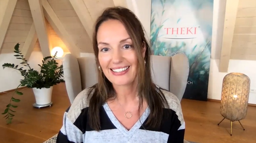 Sandra Frau braune Haare lächelt vor Steinhintergrund