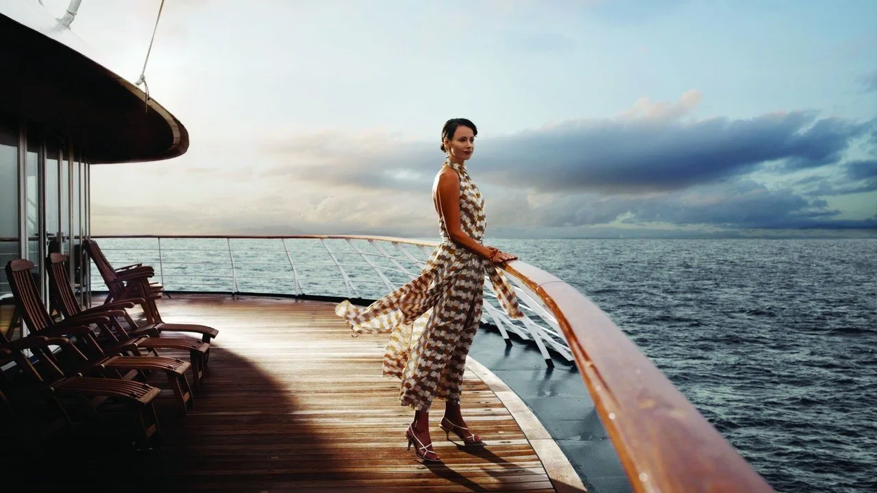 Frau in Vintage-Kleid auf Schiffsdeck mit Meerblick, Coaching Angebot Neustart 50+
