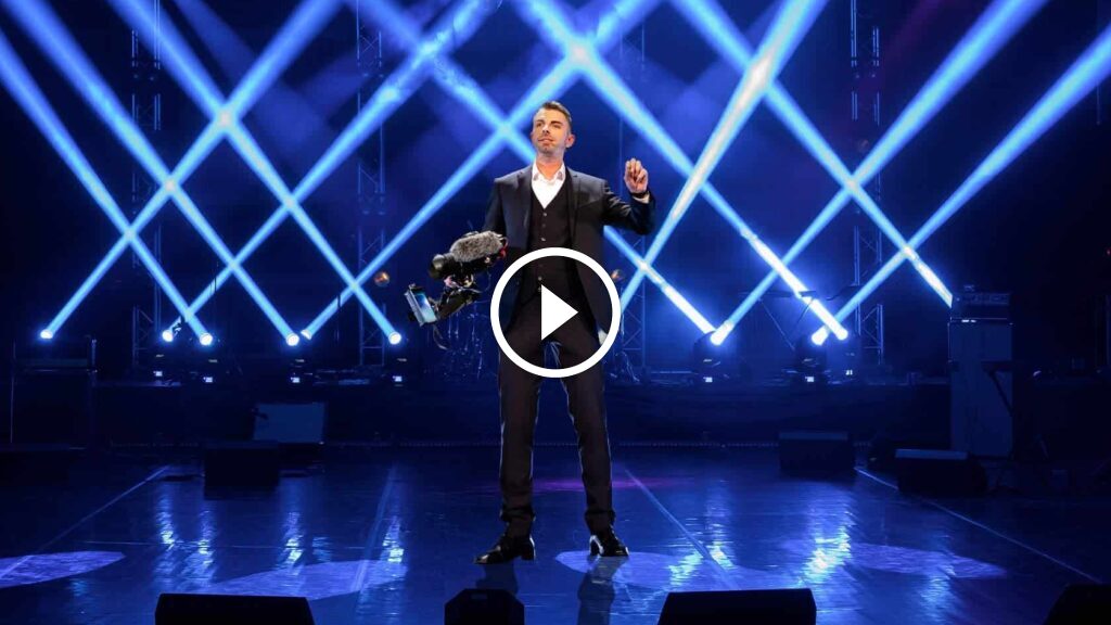 Oliver Albrecht auf Bühne mit blauem Neon-Gitter-Hintergrund, Business-Mentor Keynote