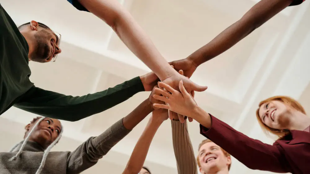 Diverse Gruppe von Menschen beim Team-Handshake von unten fotografiert
