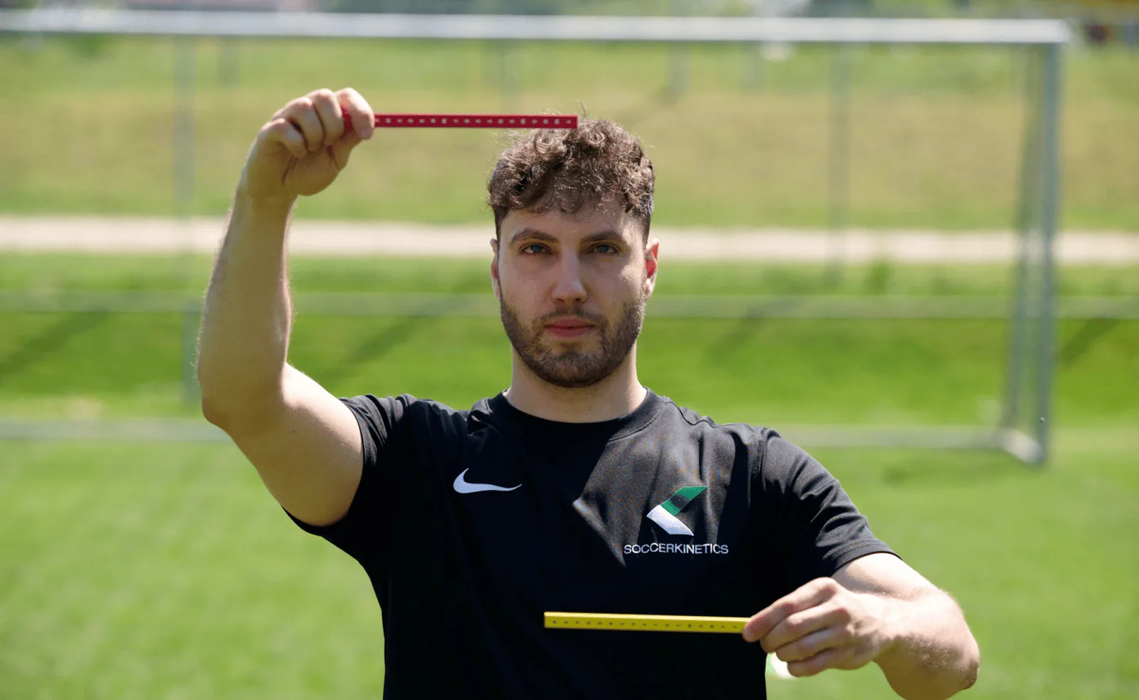 Trainer hält Visionsticks und Messstab beim Fußballtraining