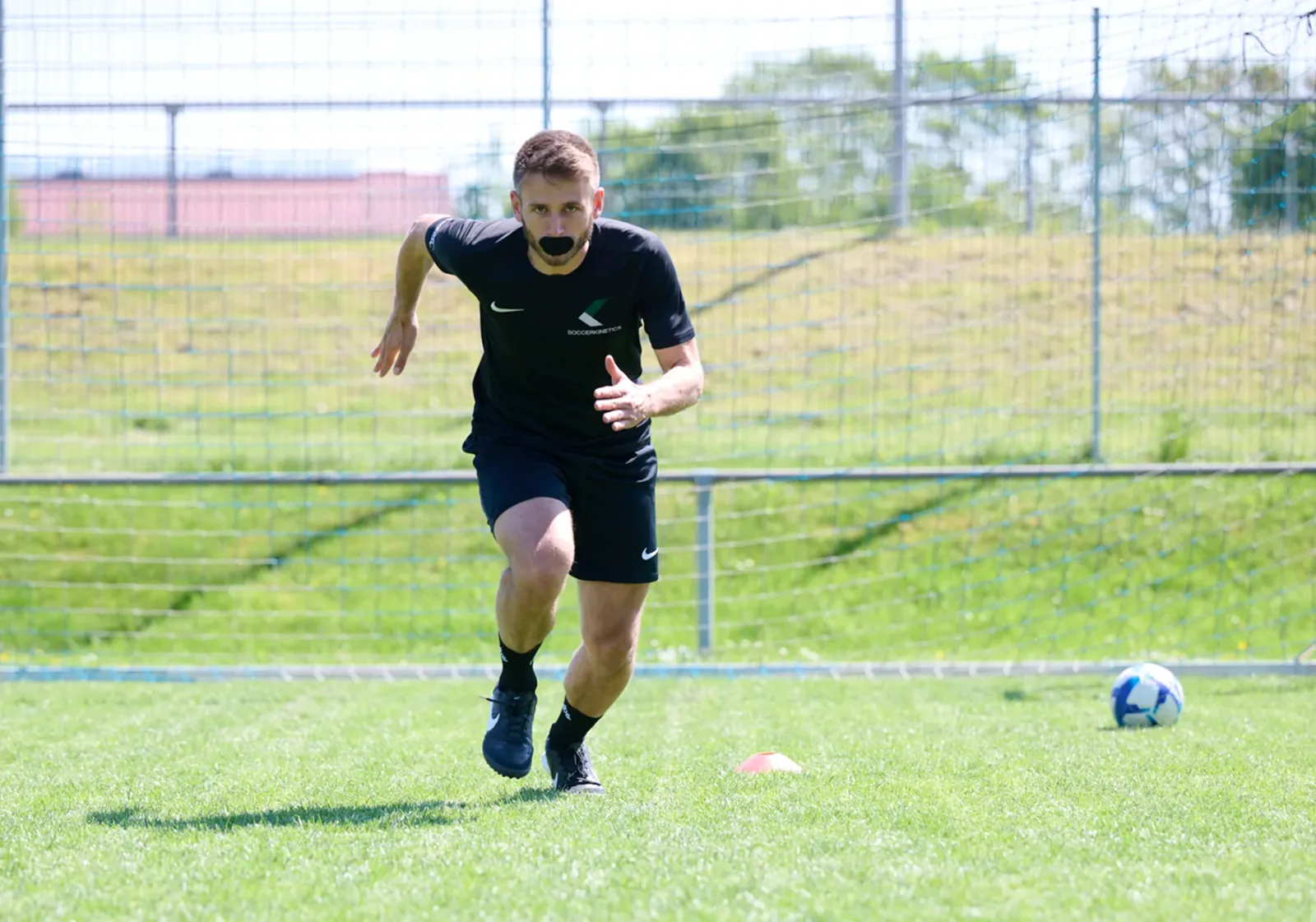 Fußballspieler mit schwarzem Mouthpiece beim Training auf grünem Platz