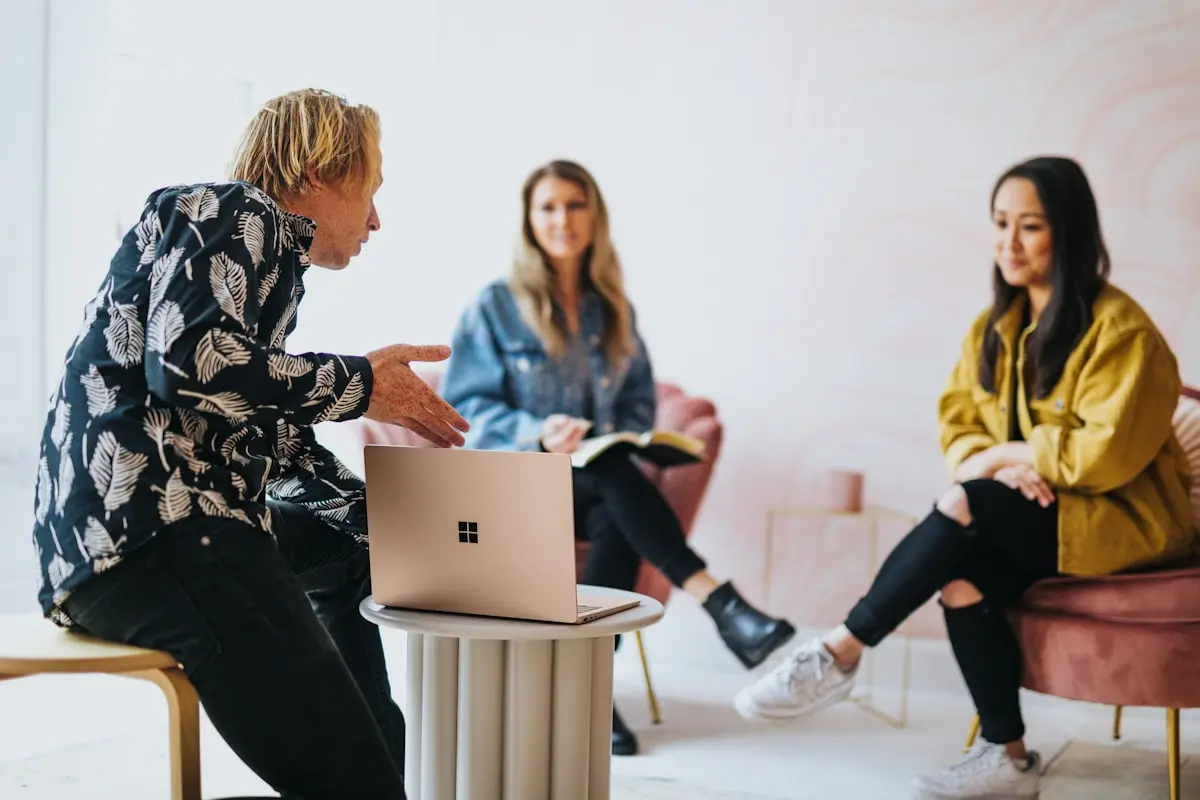 Frau mit Laptop präsentiert vor zwei sitzenden Frauen in modernem Büro