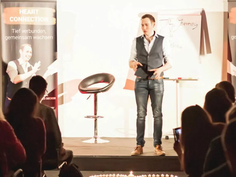 SPS Alumni Johannes Decker spricht auf Bühne mit Flipchart, Heart Connection Schrift