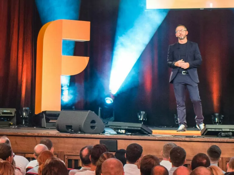 SPS Alumni Thilo Siekmann spricht auf Bühne mit großem F-Logo und Publikum