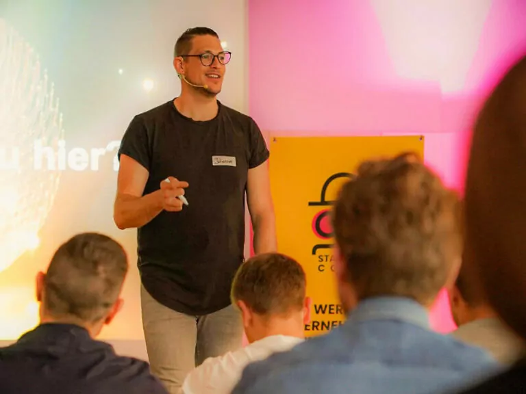 SPS Alumni Johannes Ellenberg spricht vor Publikum mit pinker Beleuchtung
