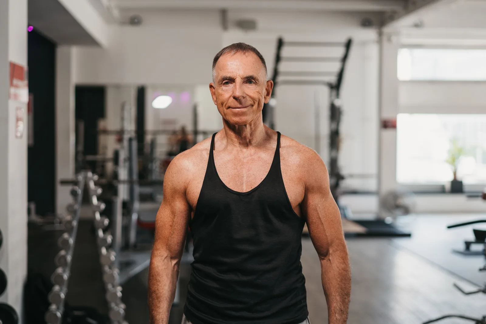 Älterer Mann in schwarzem Trainingstop im Fitnessstudio