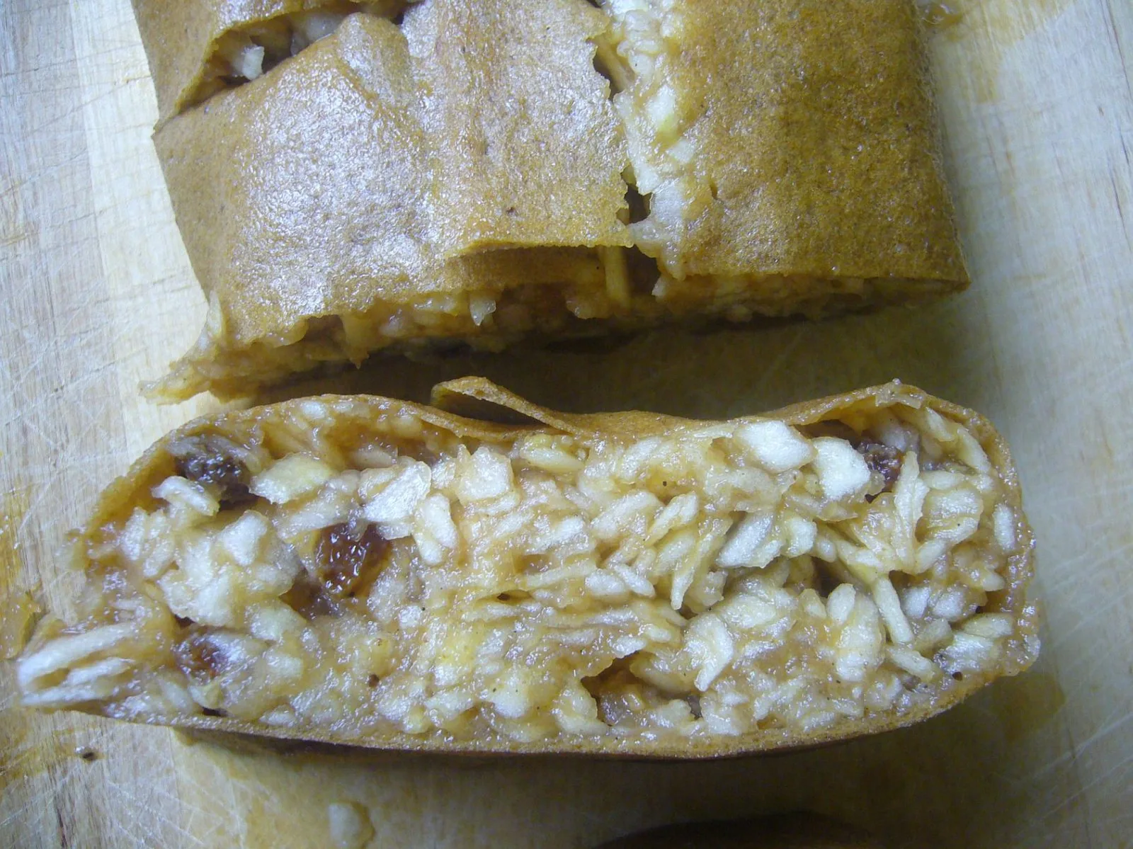 Aufgeschnittenes rohveganes Apfelstrudel-Rezept mit Apfel- und Nussfüllung, mit Puderzucker bestäubt