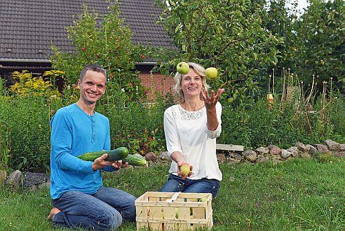 Ehepaar Antje und Ronny Düwel mit Gemüse und Holzkiste im Garten