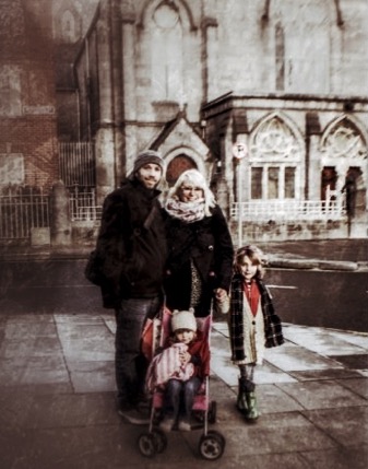 Familie mit Kinderwagen vor historischer Kirche in Syrakus