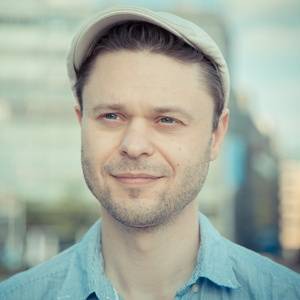 Porträtfoto von Timo Kosiol mit Stirnband im urbanen Hintergrund
