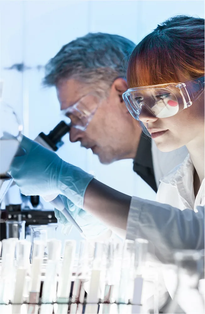 Frau und Mann mit Schutzbrille im Labor bei wissenschaftlichen Experimenten