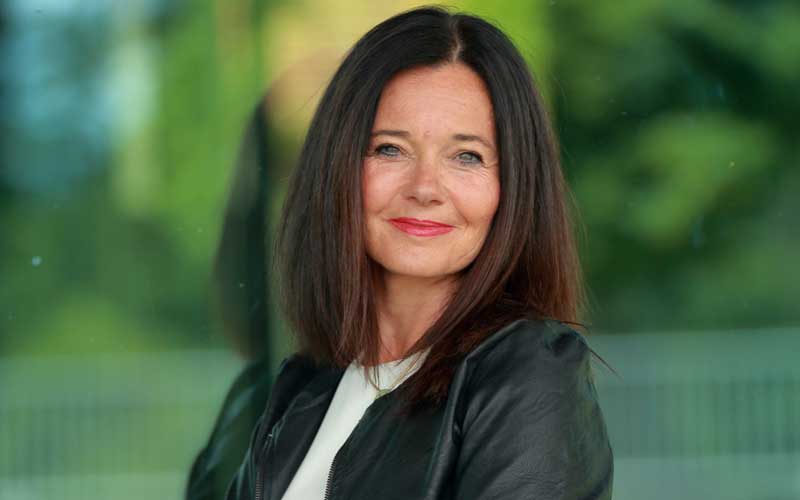 Porträt von Petra Dieme, Therapeutin mit dunklen Haaren im grünen Hintergrund