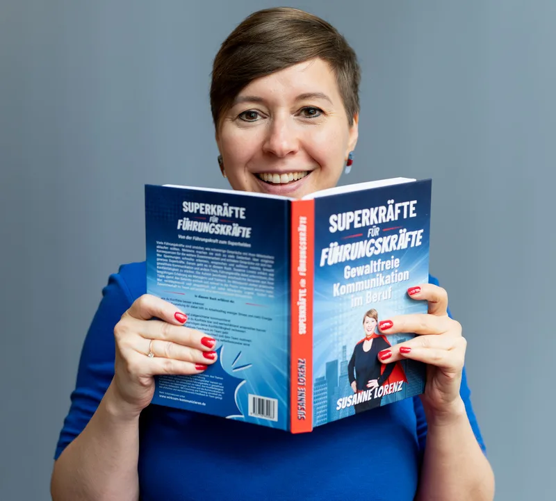 Susanne Lorenz hält aufgeschlagenes Buch Superkräfte für Führungskräfte