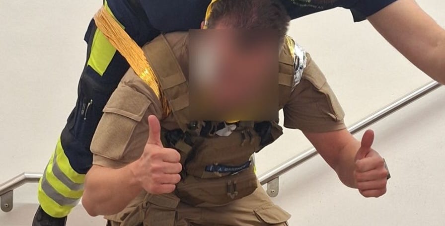 Soldat in Uniform gibt Daumen hoch, trägt taktisches Medizin-Equipment