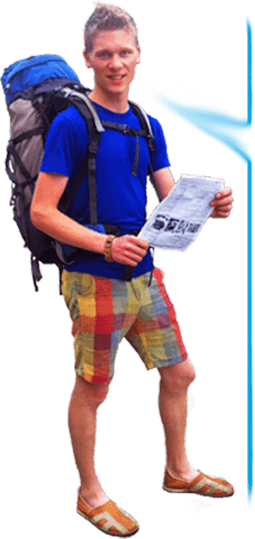 Junger Mann mit Rucksack hält Lernmaterial für Thailand-Reise in der Hand