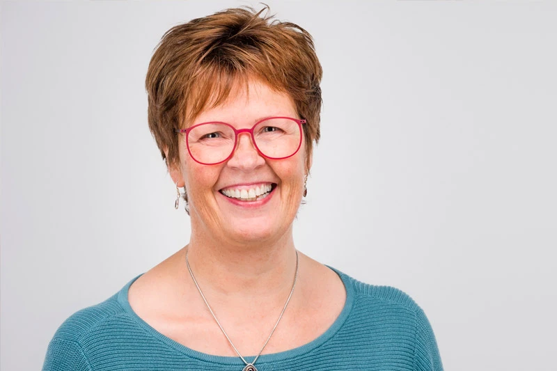 Frau mit rosaroter Brille und Zahnspange, türkisblauer Top
