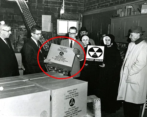 Schwarzweiß-Archivfoto von Männern mit Fallout-Shelter-Schild und Behältern