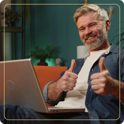 Mann mit Brille vor Laptop zeigt Daumen hoch, professionelle Umgebung