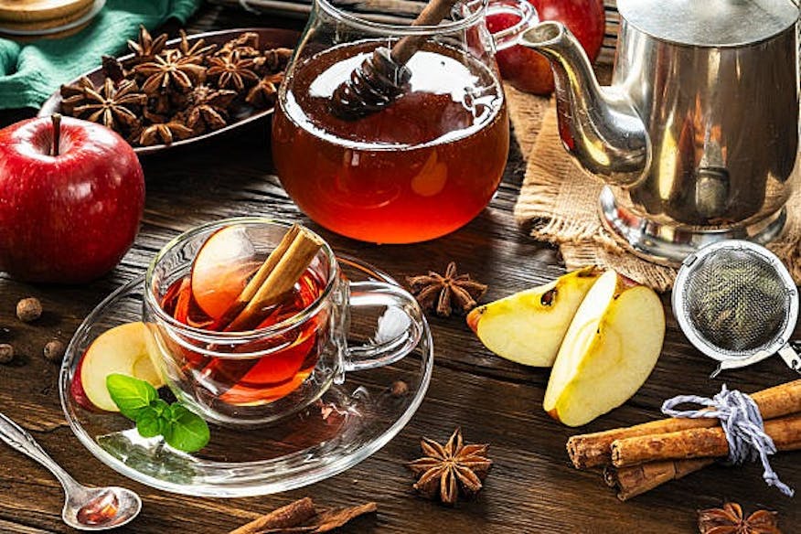 Tasse roter Tee mit Äpfeln, Zimt und Sternanis auf Holztisch