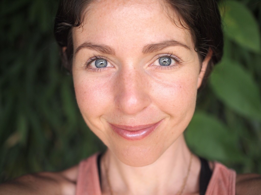 Nahaufnahme einer Frau mit natürlichem Make-up vor grünem Hintergrund