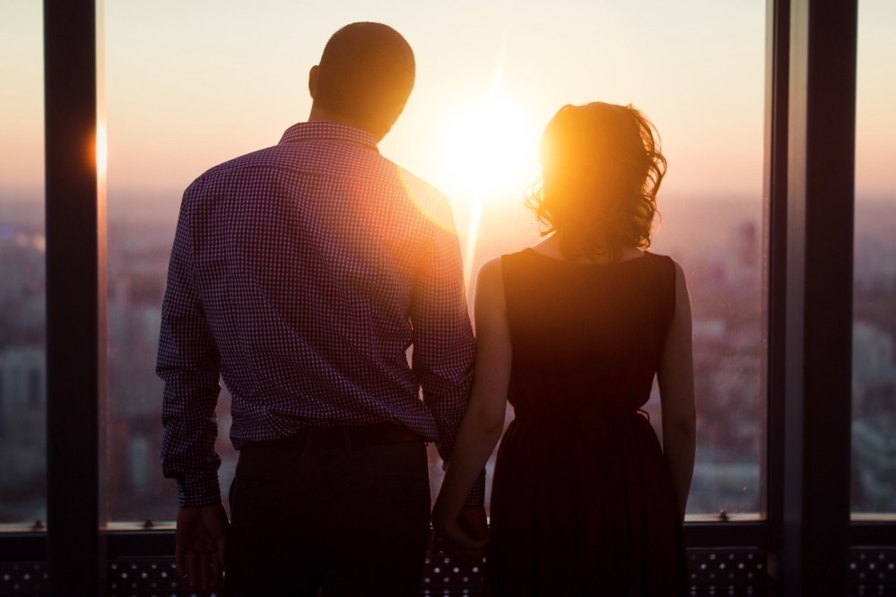 Paar in Silhouette vor Sonnenuntergang mit Stadtblick, Fensterrahmen, Beziehung