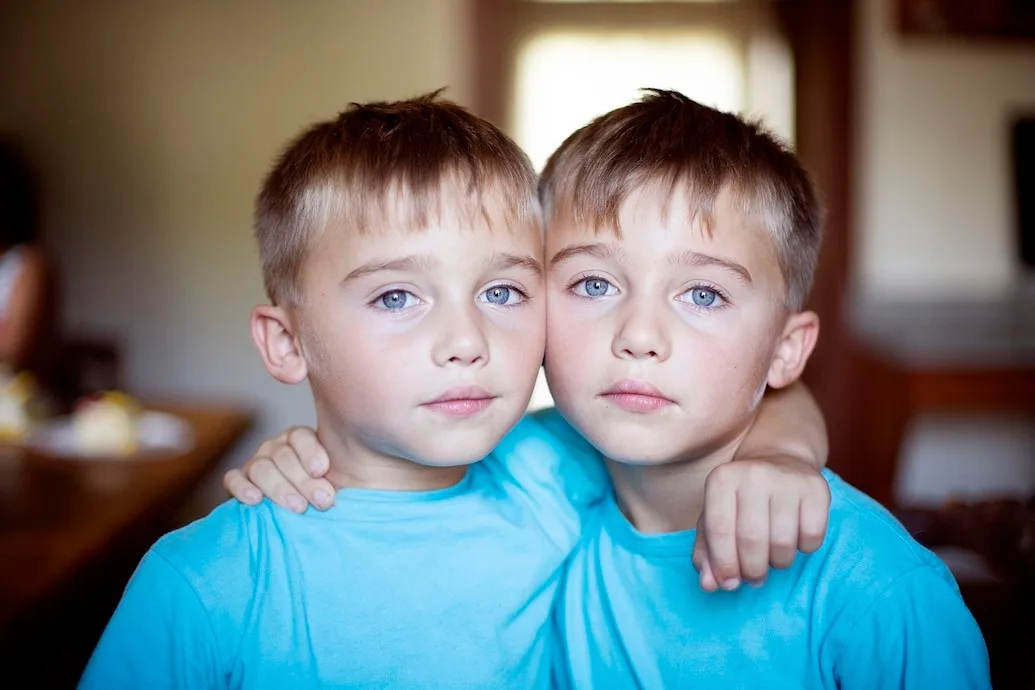 Zwei identische Jungen mit blauen Augen in hellblauen Shirts, Zwillinge Porträt