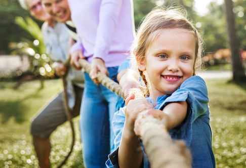 Kind zieht Seil mit Familie im Hintergrund, Generationen Tauziehen Spiel