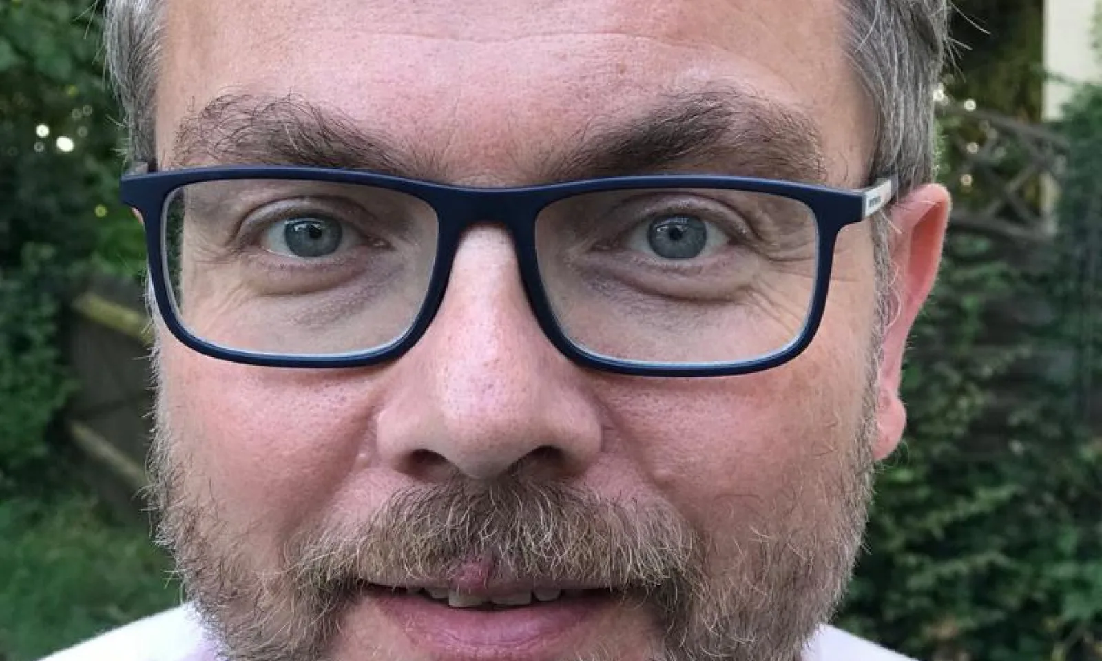 Porträt von Dr. Martin Burkhardt mit Brille vor grünem Hintergrund