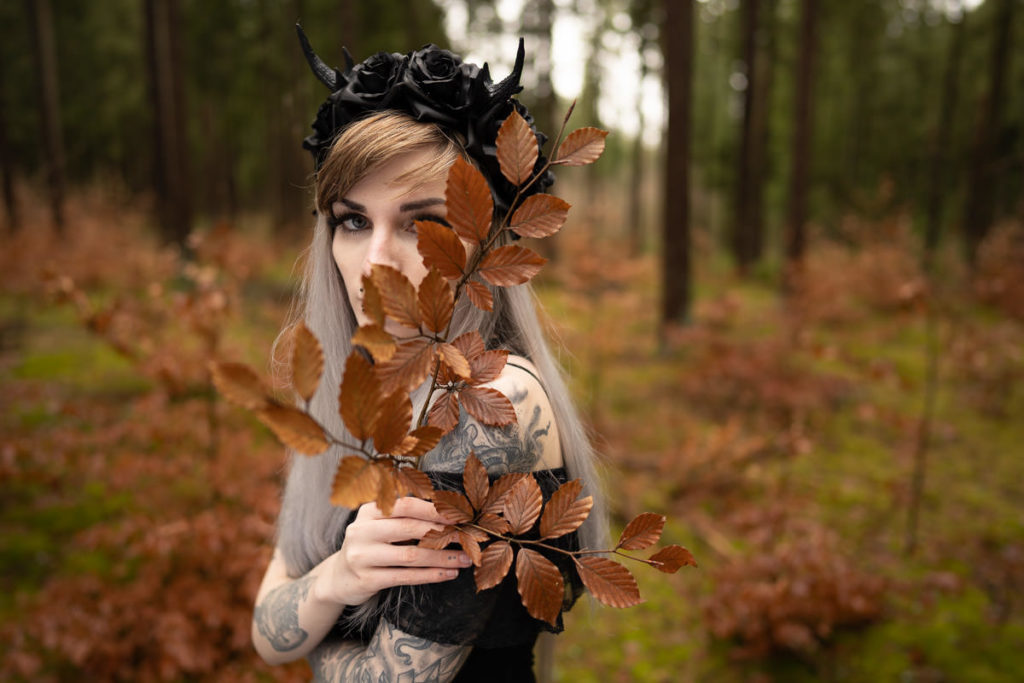 Frau mit Hörnern und Herbstblättern im Wald mit düsterem Preset-Look