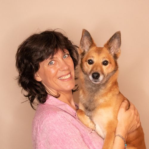 Kalyani Kathleen Reinhold mit braun-rotem Hund vor beigem Hintergrund