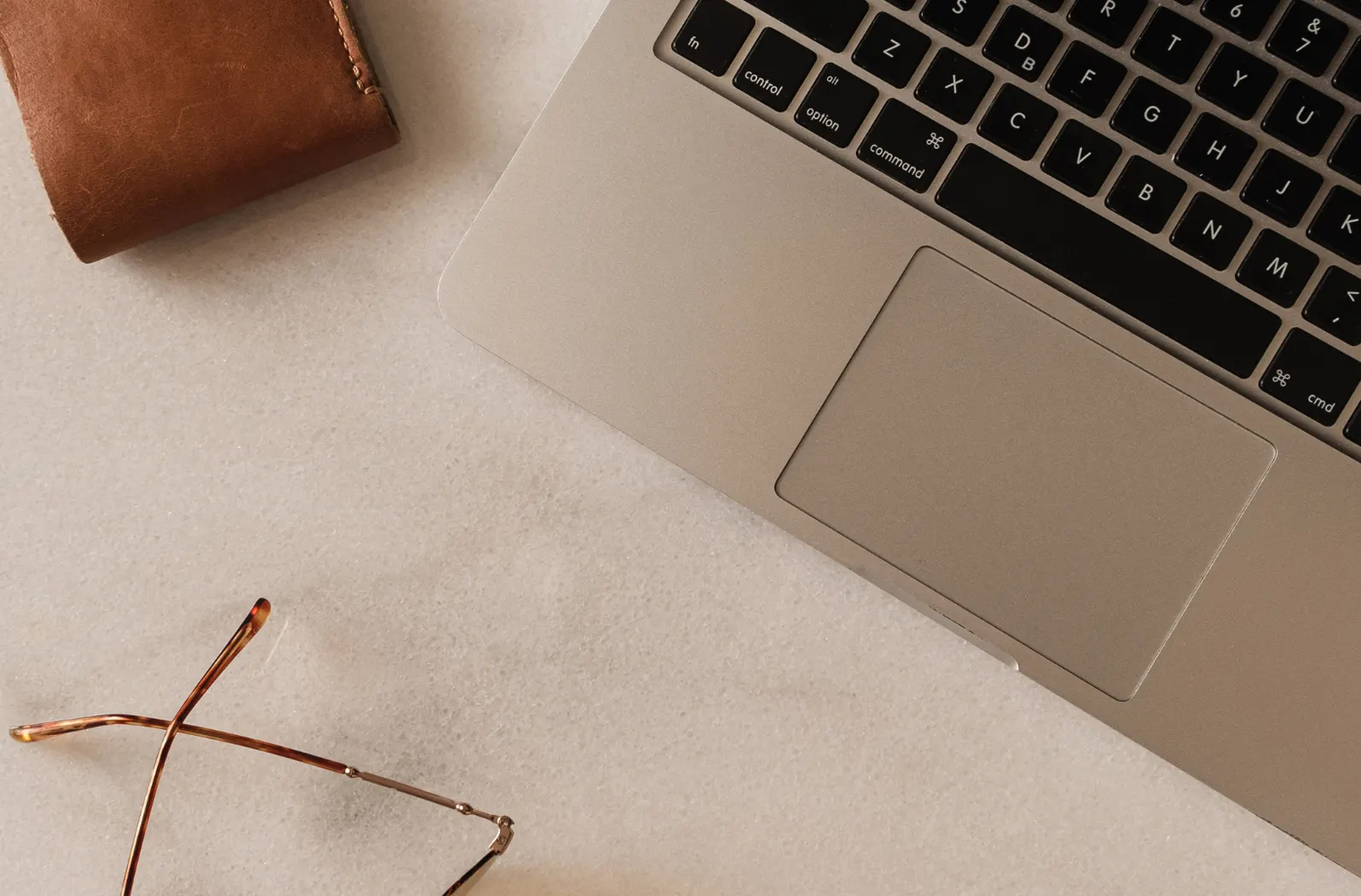 Arbeitsplatz mit Laptop, Brille, Stift und Kaffee auf Holztisch