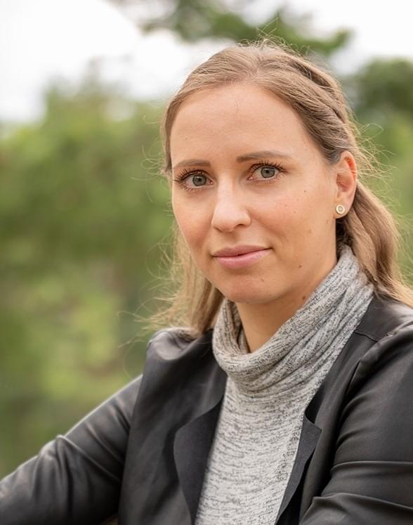 Porträtfoto einer Frau mit grauem Schal vor grünem Hintergrund