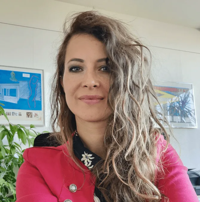 Porträtfoto einer Frau in pinkfarbener Jacke mit Blumenstickerei
