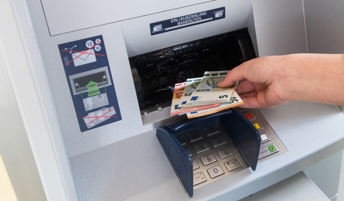 Hand zieht Geldscheine aus Geldautomat, ATM-Interface sichtbar