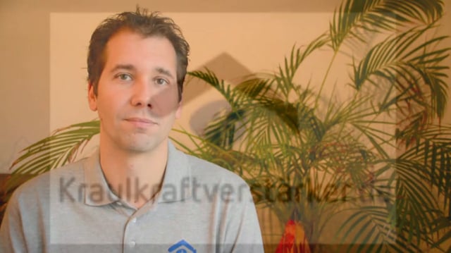 Mann in grauem Shirt mit Pflanzendekoration im Hintergrund