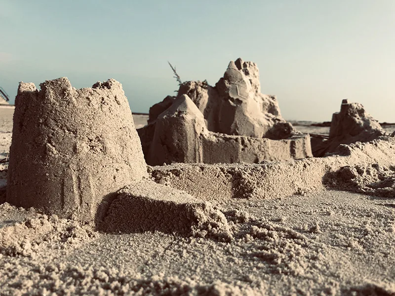 Zerbrochene Sandburg am Strand mit bewölktem Himmel