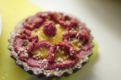 Rosa Rohkost-Torte mit strukturierter Oberfläche auf gelbem Untergrund
