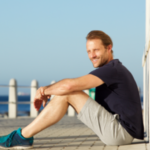 Mann sitzt am Wasser mit Meer im Hintergrund – Kundenstimme