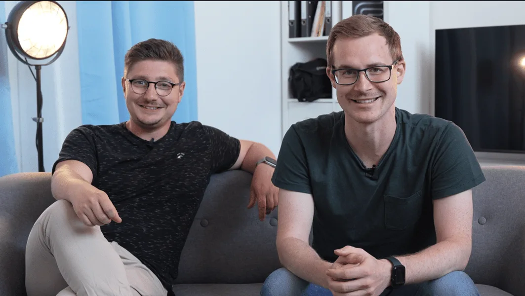 UGC Videokurs – Kurs zu User Generated Content von Simon Knobloch 1 Zwei Männer sitzen auf grauem Sofa vor Studio-Beleuchtung und lächeln in Kamera