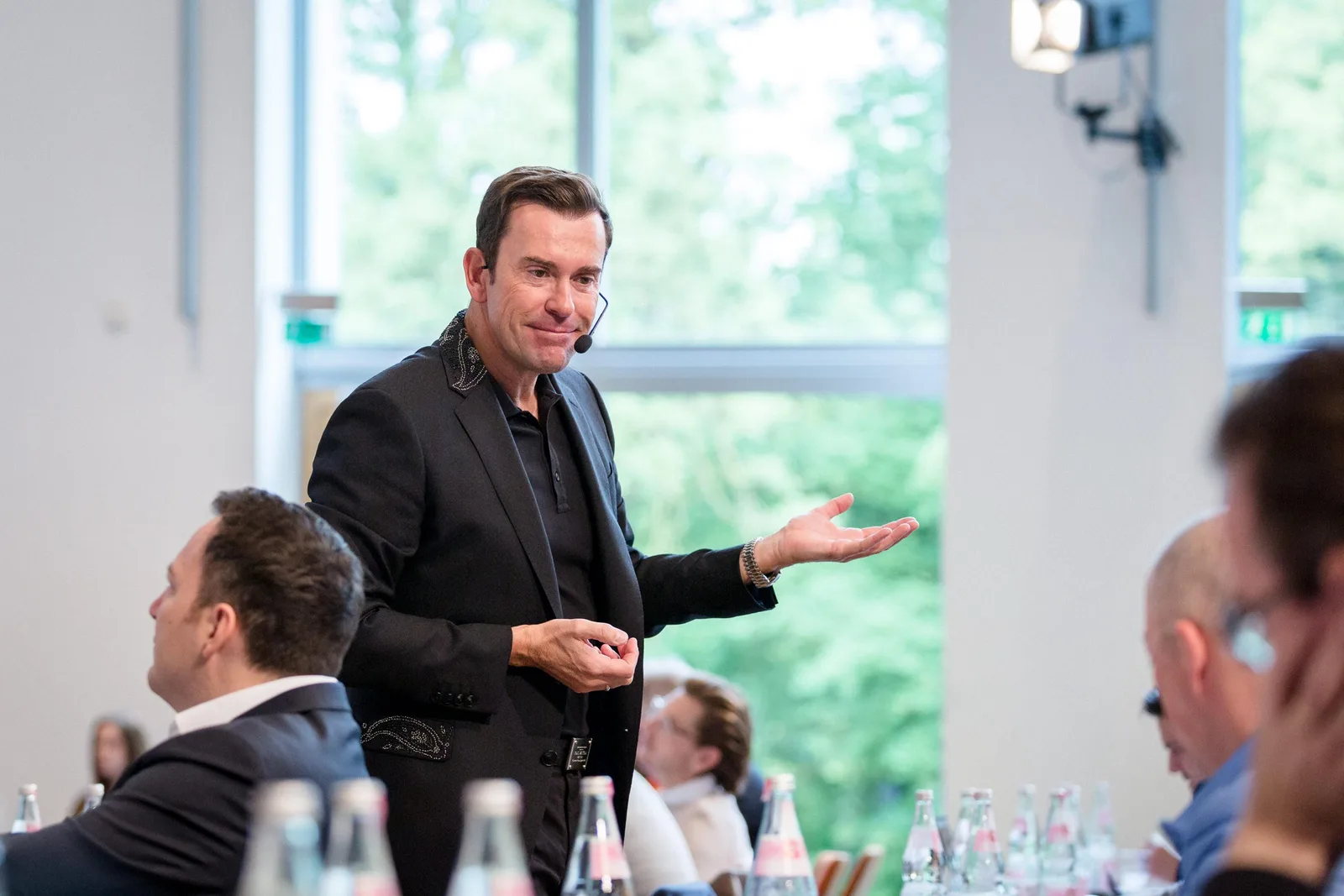 Und immer wieder aufstehen – E-Book über Krisenbewältigung 8 Jürgen Höller mit Headset präsentiert vor Publikum in hellem Konferenzraum