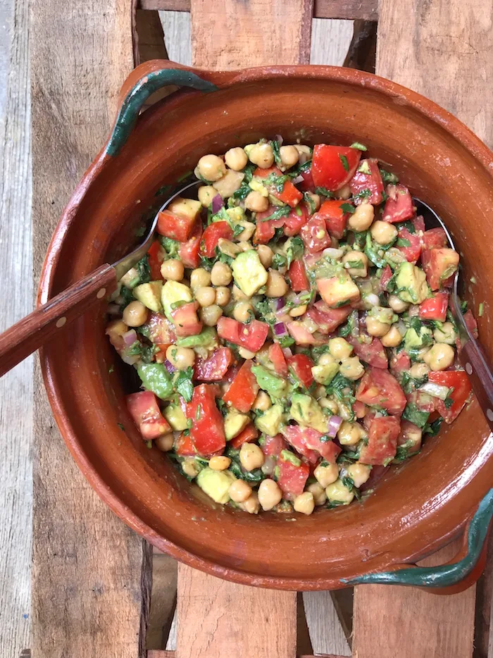 Veganer Kichererbsen-Salat in terrakottafarbener Schale mit Kichererbsen, Tomaten, Gurke und Kräutern