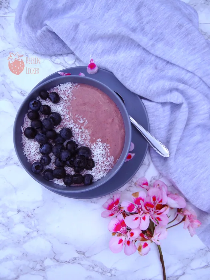 Vegane Johannisbeer-Smoothie-Bowl mit lila Base, Kokosflocken und schwarzen Beeren